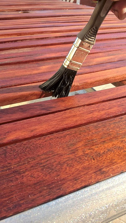 brush applying warm toned stain to wood